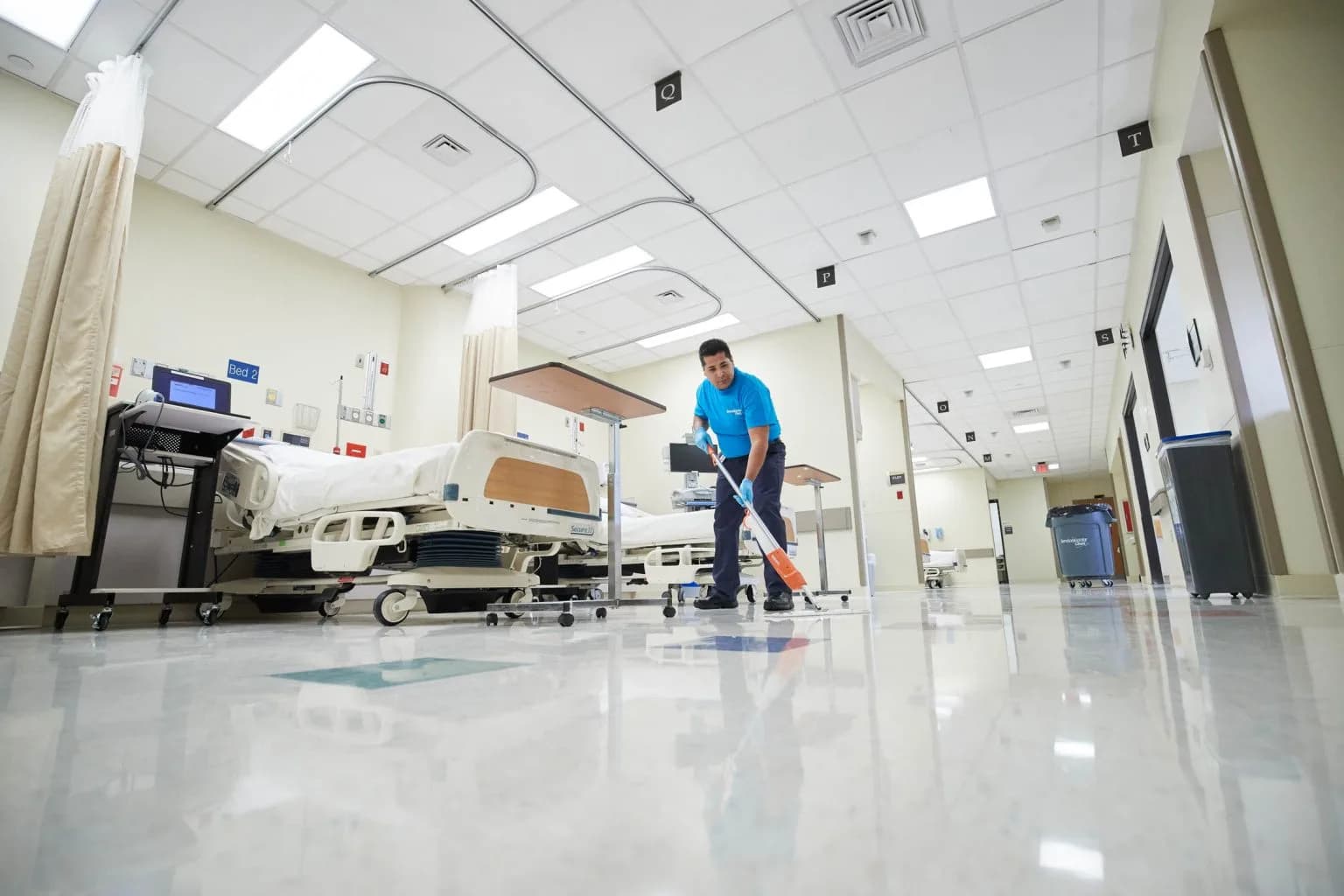 Mega Service Solutions technician mopping hospital ward floor — HIPAA-compliant medical cleaning